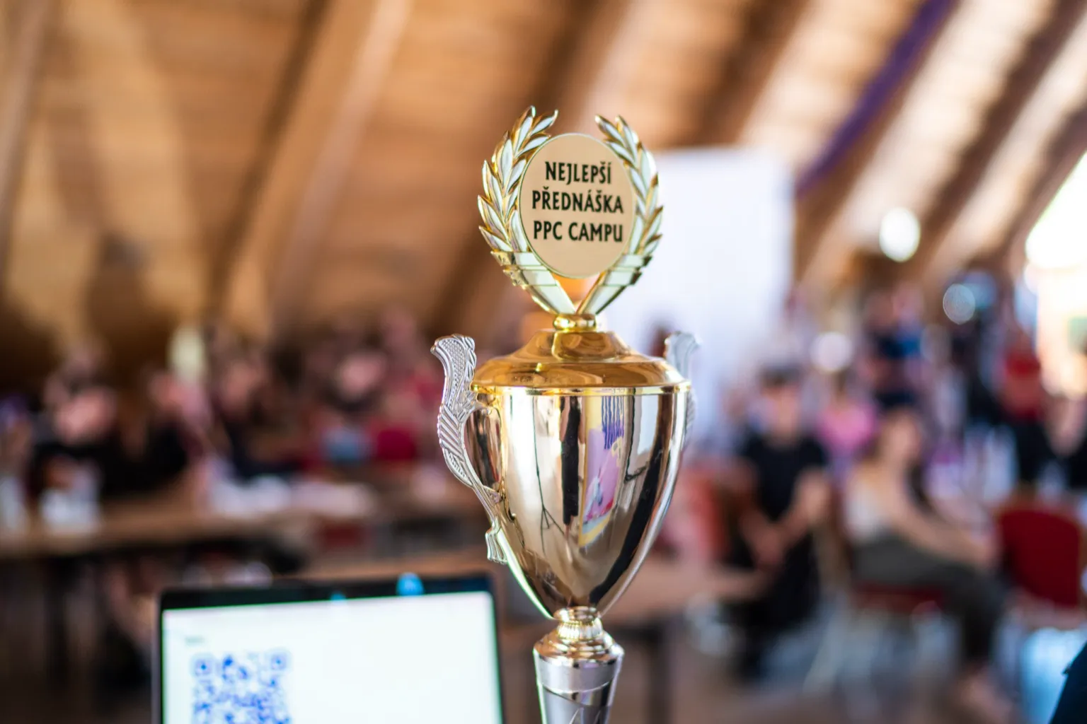 The best-talk cup of PPC camp 2026 standing in front of the audience in a wooden hall