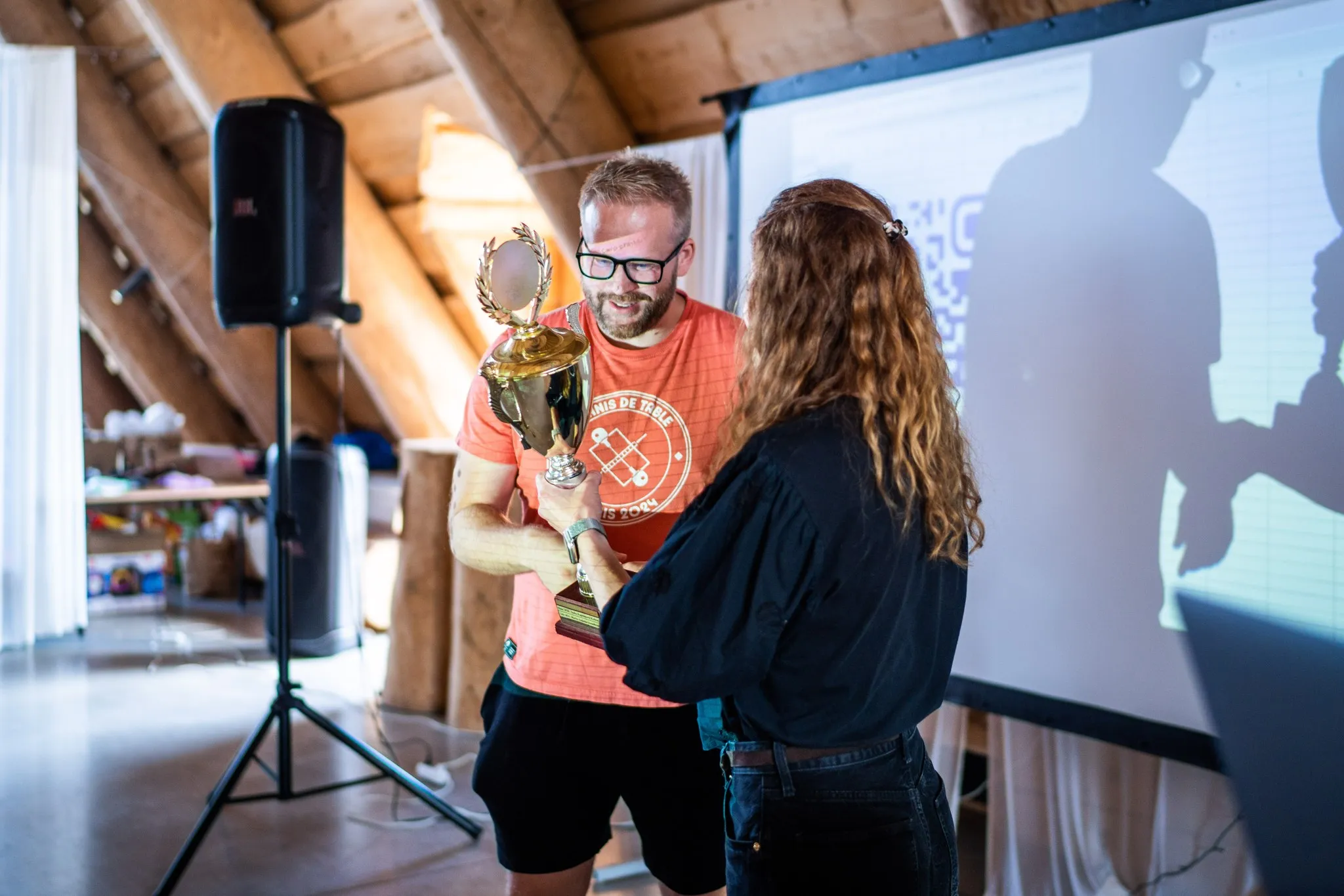 Markéta Kabátová of uLab handing Jakub Kašparů the best-talk cup in the wooden hall at PPC camp 2026